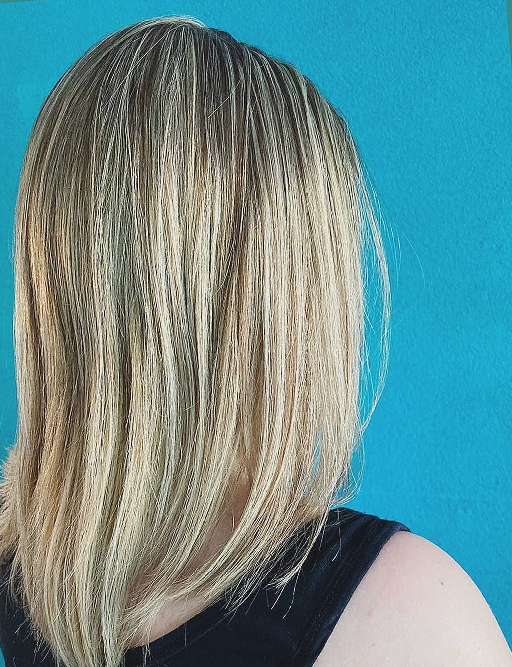 Blonde lob met lichte lokken, van opzij gezien voor een turquoise muur