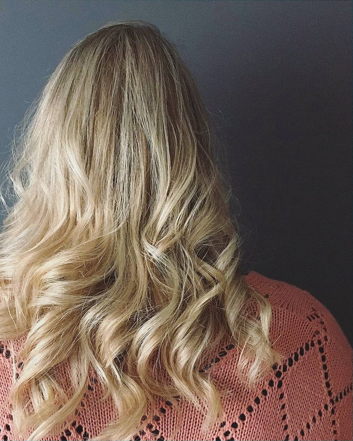 Lang blond haar in losse krullen, van achteren gezien