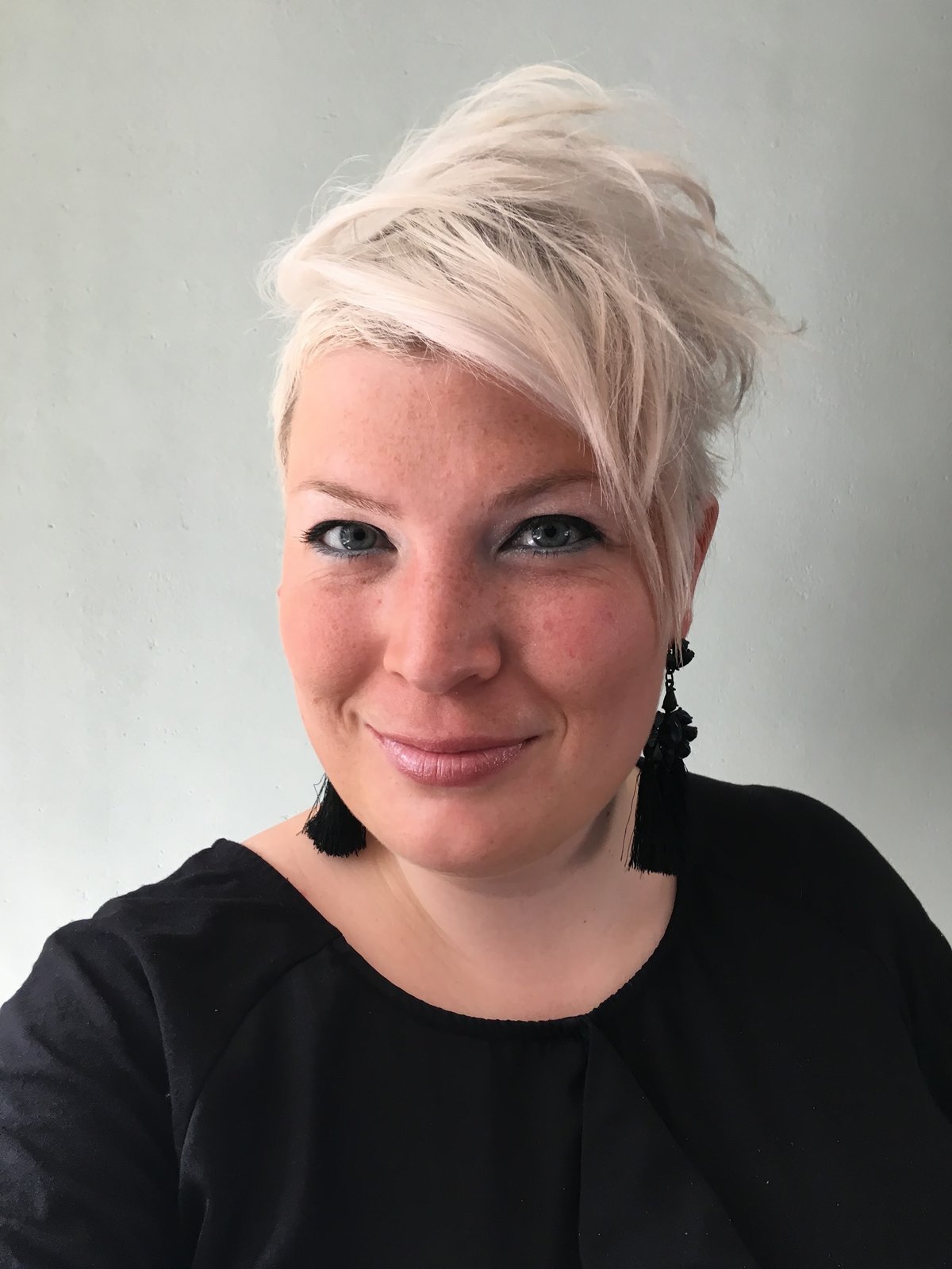 Alissa Beugelink, met kort platinablond haar, glimlachend in een zwarte top